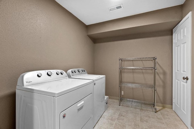 clothes washing area featuring light tile patterned flooring and washing machine and dryer