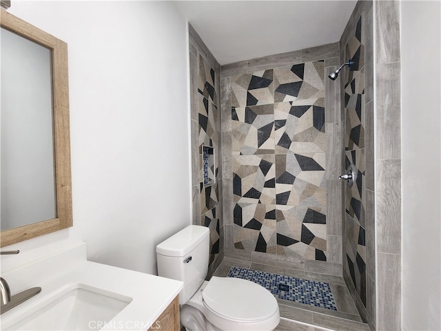 bathroom featuring a tile shower, toilet, and vanity