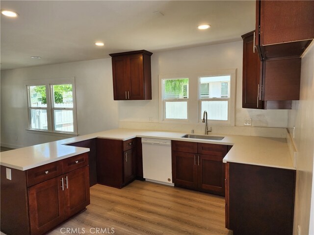 kitchen with dark brown cabinetry, kitchen peninsula, dishwasher, light wood-type flooring, and sink