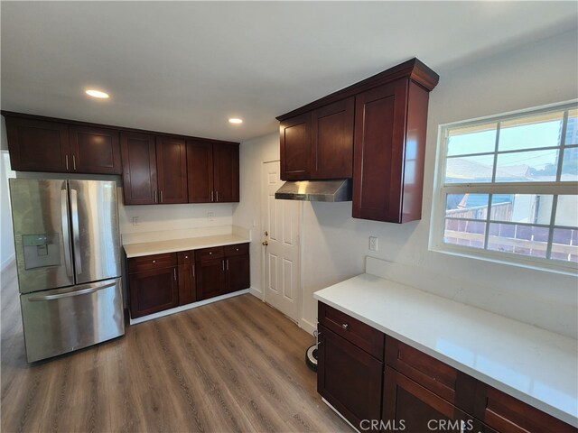 kitchen with wall chimney range hood, stainless steel fridge with ice dispenser, and hardwood / wood-style floors