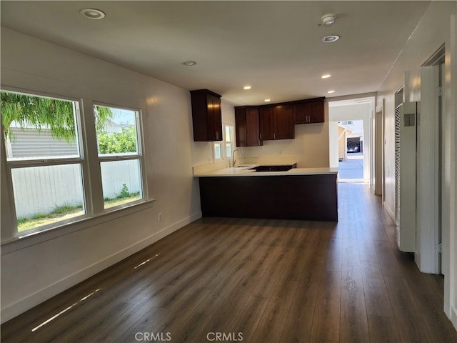 kitchen featuring dark brown cabinetry, dark hardwood / wood-style flooring, and kitchen peninsula