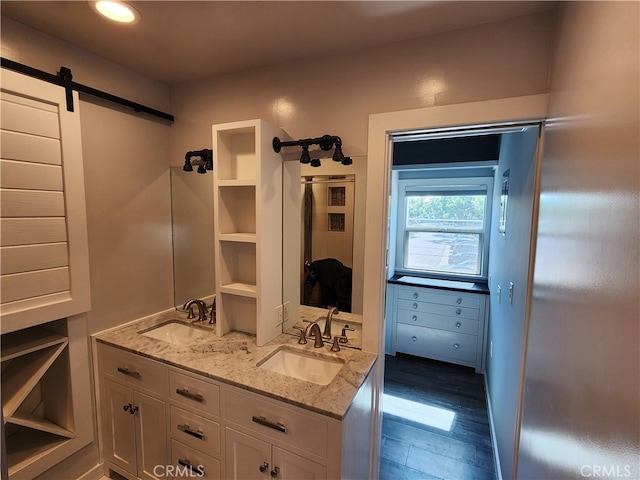 interior space featuring dark hardwood / wood-style floors, light stone countertops, a barn door, white cabinets, and sink