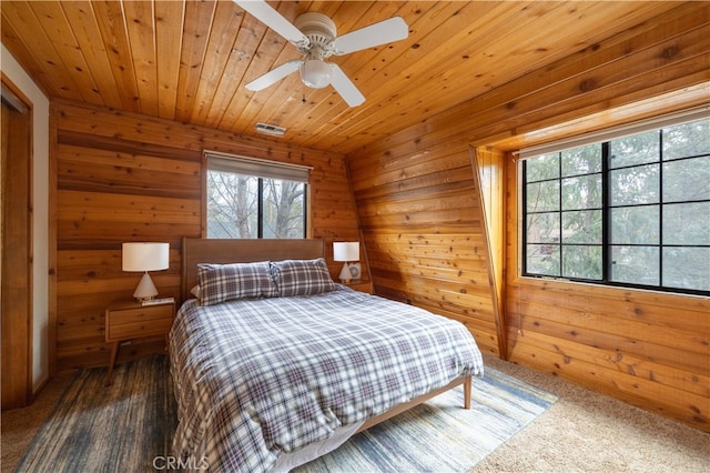 carpeted bedroom featuring ceiling fan, wood ceiling, and wooden walls