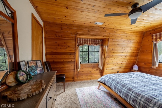 carpeted bedroom with ceiling fan, wood walls, and wooden ceiling