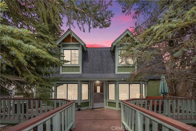 back house at dusk featuring a deck