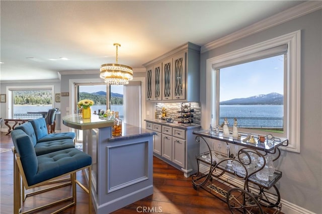 bar with a notable chandelier, hanging light fixtures, gray cabinetry, a water view, and dark hardwood / wood-style flooring