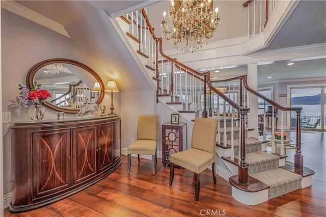 sitting room with ornamental molding, a towering ceiling, hardwood / wood-style floors, and a chandelier