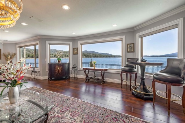 living area featuring dark wood-type flooring, ornamental molding, a water view, and a notable chandelier