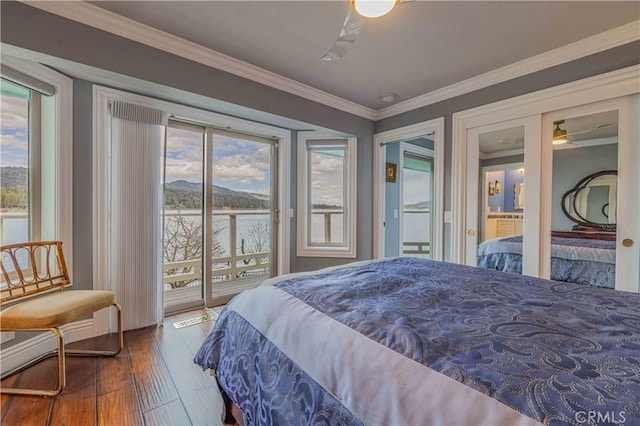 bedroom with dark wood-type flooring, a water view, access to outside, and multiple windows