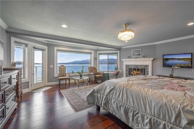 bedroom featuring access to exterior, a stone fireplace, crown molding, and multiple windows