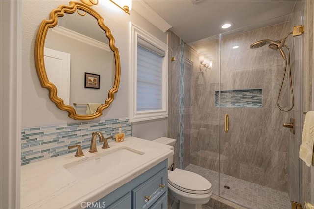 bathroom featuring vanity, tasteful backsplash, toilet, ornamental molding, and a shower with shower door