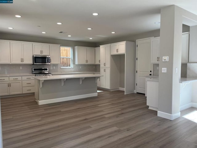 kitchen featuring white cabinets, a center island, stainless steel appliances, and dark wood-type flooring