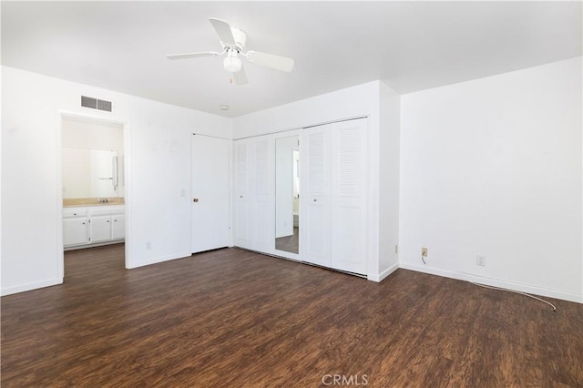 unfurnished bedroom with ceiling fan, dark hardwood / wood-style floors, a closet, and ensuite bath