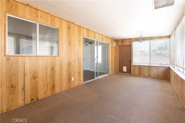 unfurnished room featuring ceiling fan, carpet floors, and wooden walls