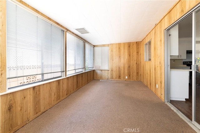 spare room featuring light colored carpet and wood walls