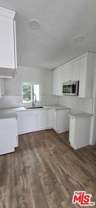 kitchen with backsplash, sink, white cabinetry, and dark hardwood / wood-style floors