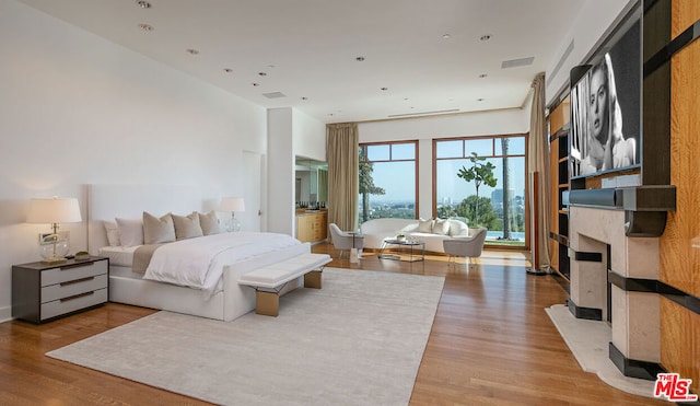 bedroom with light wood-type flooring and a high end fireplace