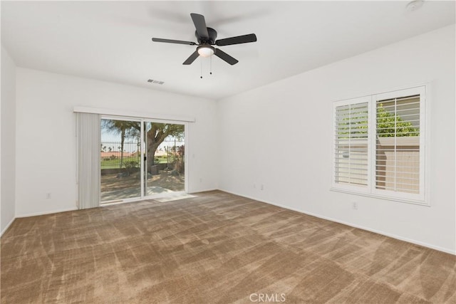 spare room featuring ceiling fan, carpet floors, and a wealth of natural light