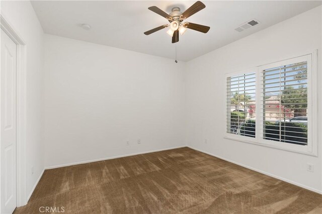 spare room featuring ceiling fan and dark carpet