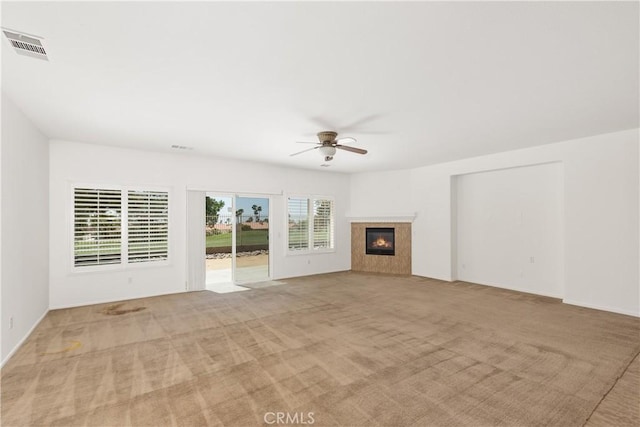 unfurnished living room featuring ceiling fan, light colored carpet, and a fireplace