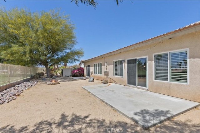 rear view of property with a patio and an outdoor fire pit