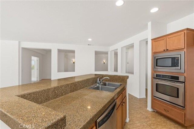 kitchen with sink, stone countertops, and appliances with stainless steel finishes