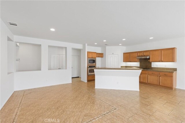 kitchen featuring tasteful backsplash, a kitchen island with sink, and stainless steel appliances