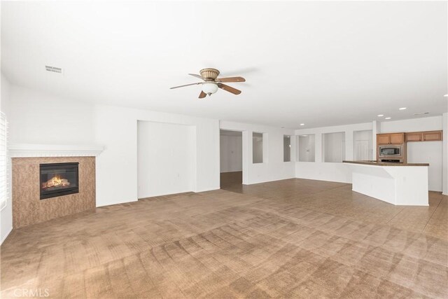 unfurnished living room with light colored carpet and ceiling fan