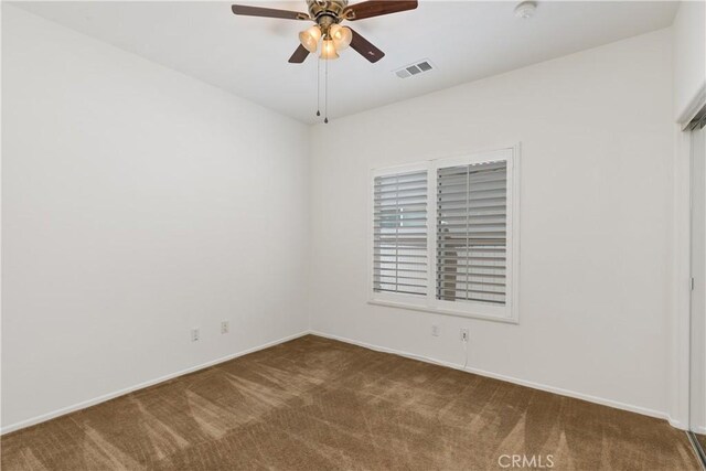 carpeted spare room featuring ceiling fan