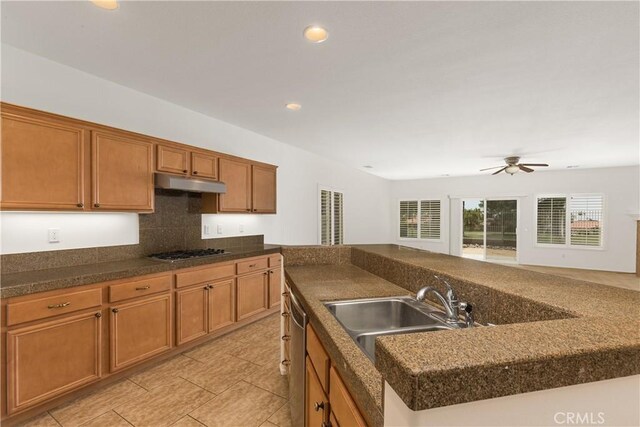 kitchen with sink, ceiling fan, appliances with stainless steel finishes, tasteful backsplash, and a center island with sink