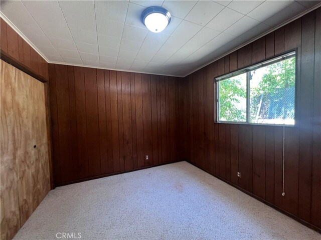 spare room with light carpet and wooden walls