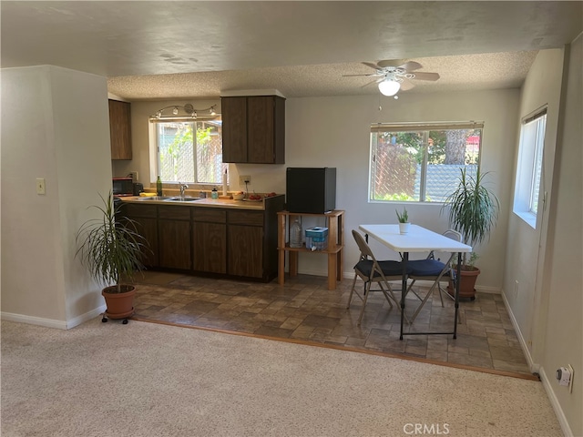 kitchen with ceiling fan, dark brown cabinetry, light tile patterned floors, sink, and a textured ceiling