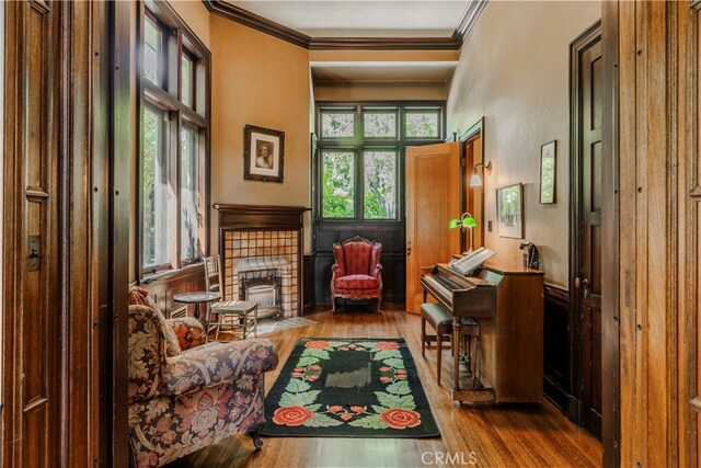 sitting room featuring a brick fireplace, plenty of natural light, ornamental molding, and light wood-type flooring