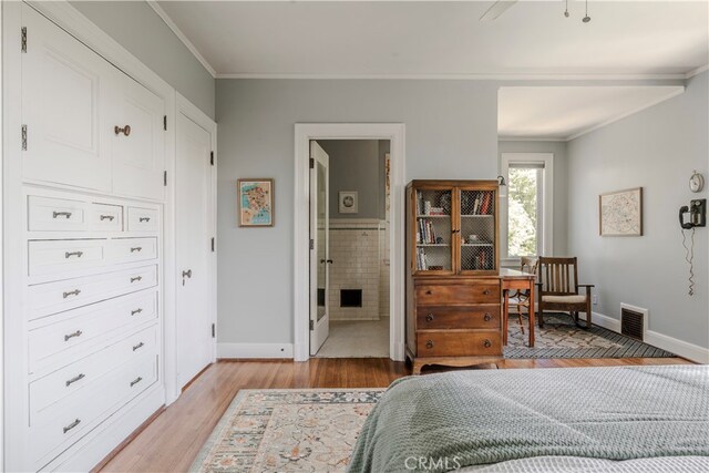 bedroom with ceiling fan, light wood-type flooring, crown molding, and ensuite bath