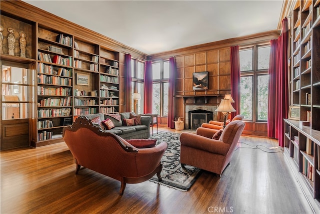 sitting room featuring wood-type flooring, built in features, and ornamental molding