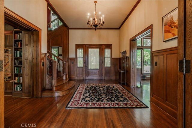 foyer featuring crown molding, dark wood-type flooring, and a notable chandelier