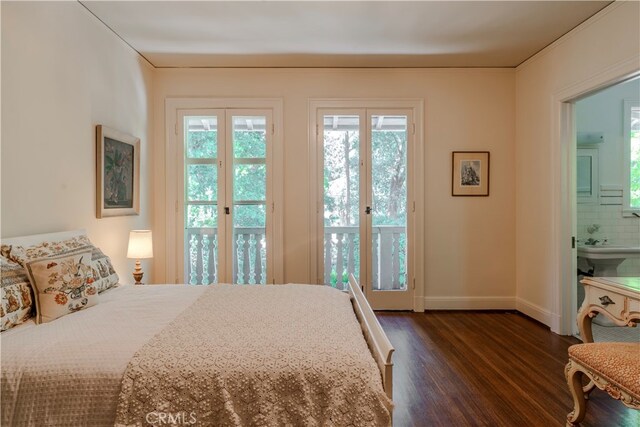 bedroom featuring french doors, dark hardwood / wood-style flooring, access to outside, and connected bathroom