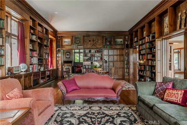 sitting room featuring hardwood / wood-style flooring, built in features, and crown molding