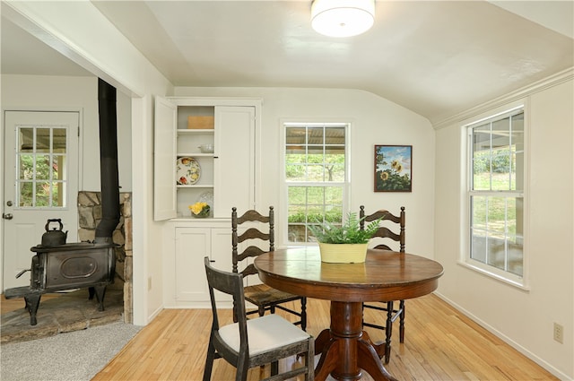 dining room featuring a wood stove, plenty of natural light, light hardwood / wood-style flooring, and lofted ceiling