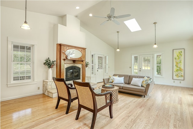 living room featuring a wealth of natural light, light wood-type flooring, a skylight, and ceiling fan