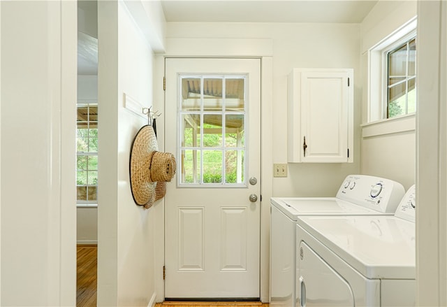 clothes washing area featuring washer and clothes dryer, hardwood / wood-style floors, plenty of natural light, and cabinets