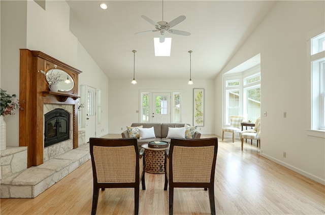 living room featuring high vaulted ceiling, ceiling fan, a fireplace, and light wood-type flooring