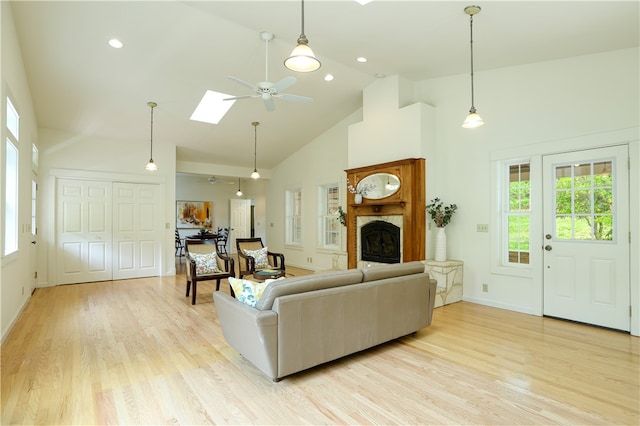 living room featuring light hardwood / wood-style floors, high vaulted ceiling, ceiling fan, and a skylight