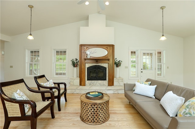 living room with high vaulted ceiling, a high end fireplace, and light hardwood / wood-style floors