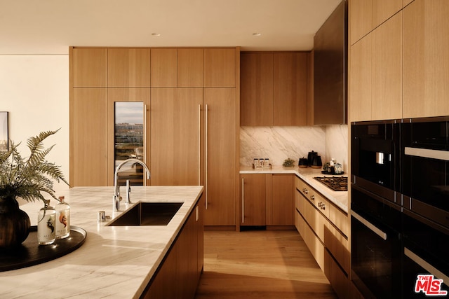 kitchen with light hardwood / wood-style floors, sink, stainless steel gas stovetop, backsplash, and oven