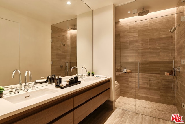 bathroom with an enclosed shower and dual vanity