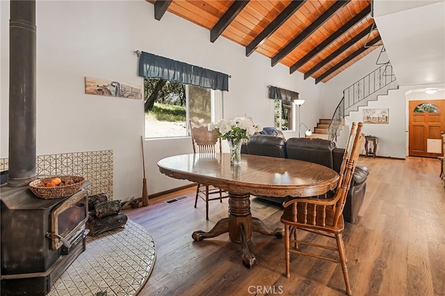 dining area featuring wood ceiling, wood-type flooring, high vaulted ceiling, a wood stove, and beam ceiling