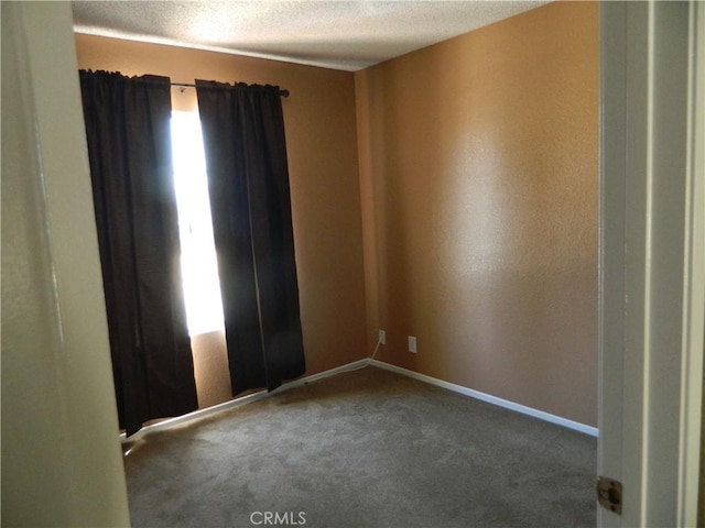 carpeted empty room featuring a textured ceiling