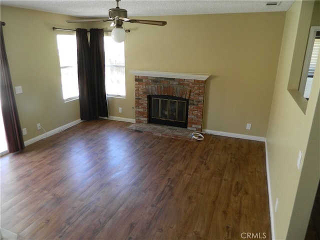 unfurnished living room with a fireplace, a textured ceiling, ceiling fan, and dark wood-type flooring