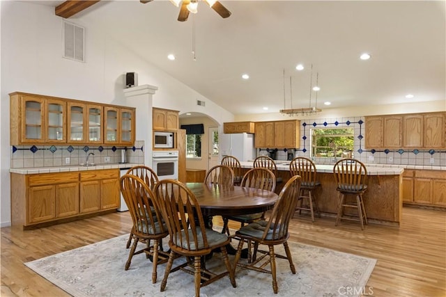 dining room with light hardwood / wood-style flooring, high vaulted ceiling, ceiling fan, and sink